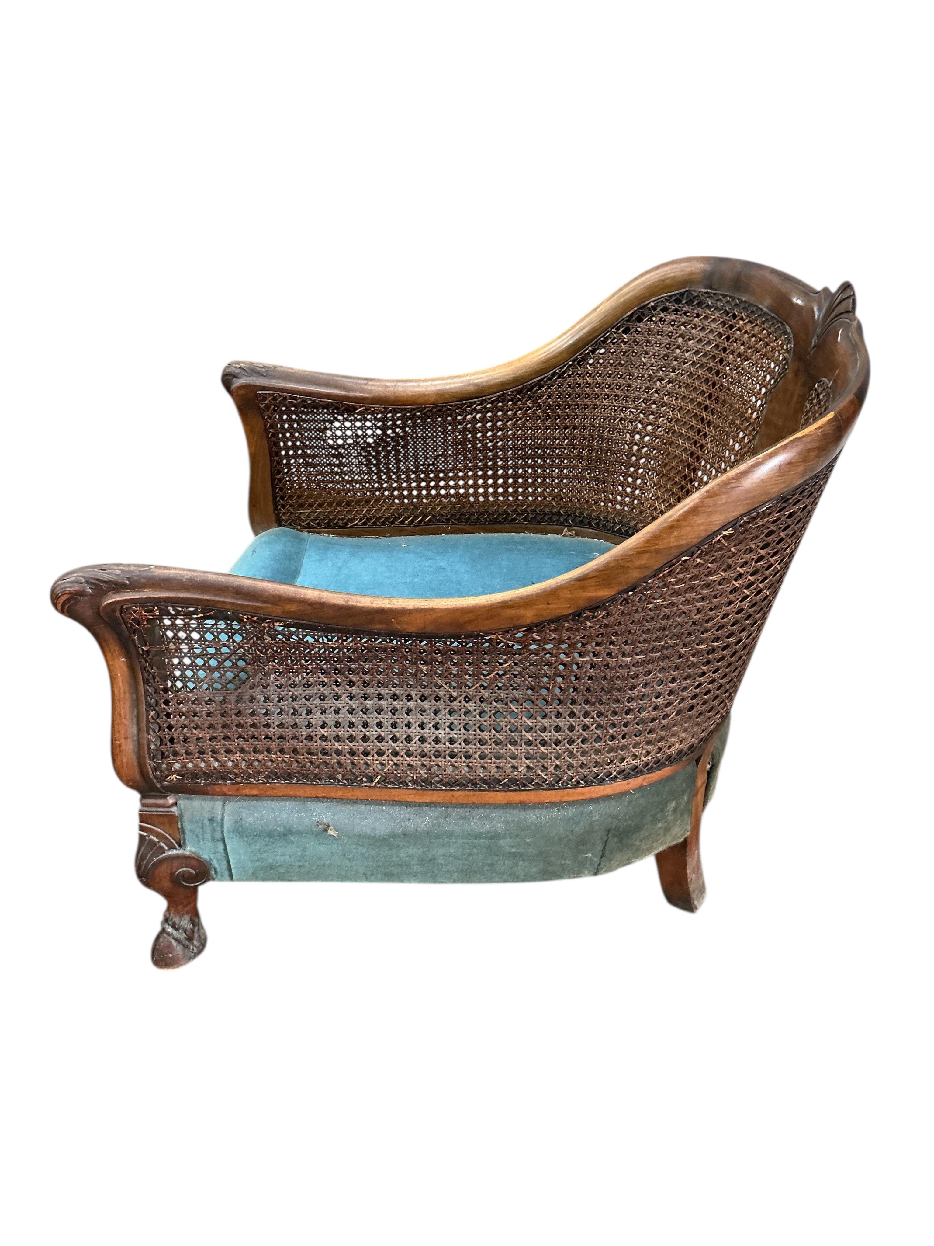 An early 20th century carved walnut and double canework three piece bergère suite, cane in need of repair